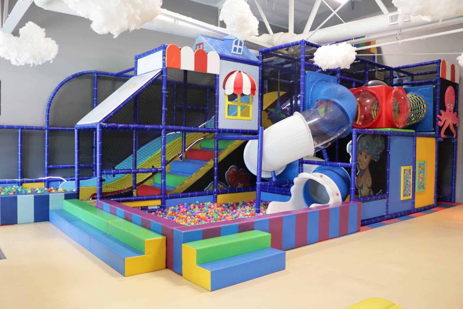 The play structure with its tube slide and the soft play area under the hanging clouds