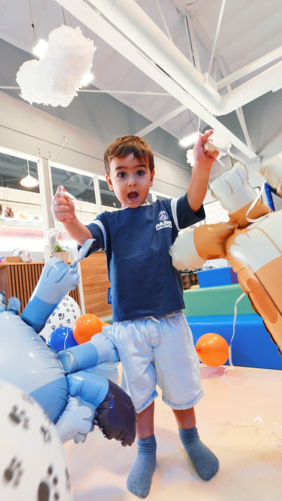 A boy with a bunch of balloons on the play floor