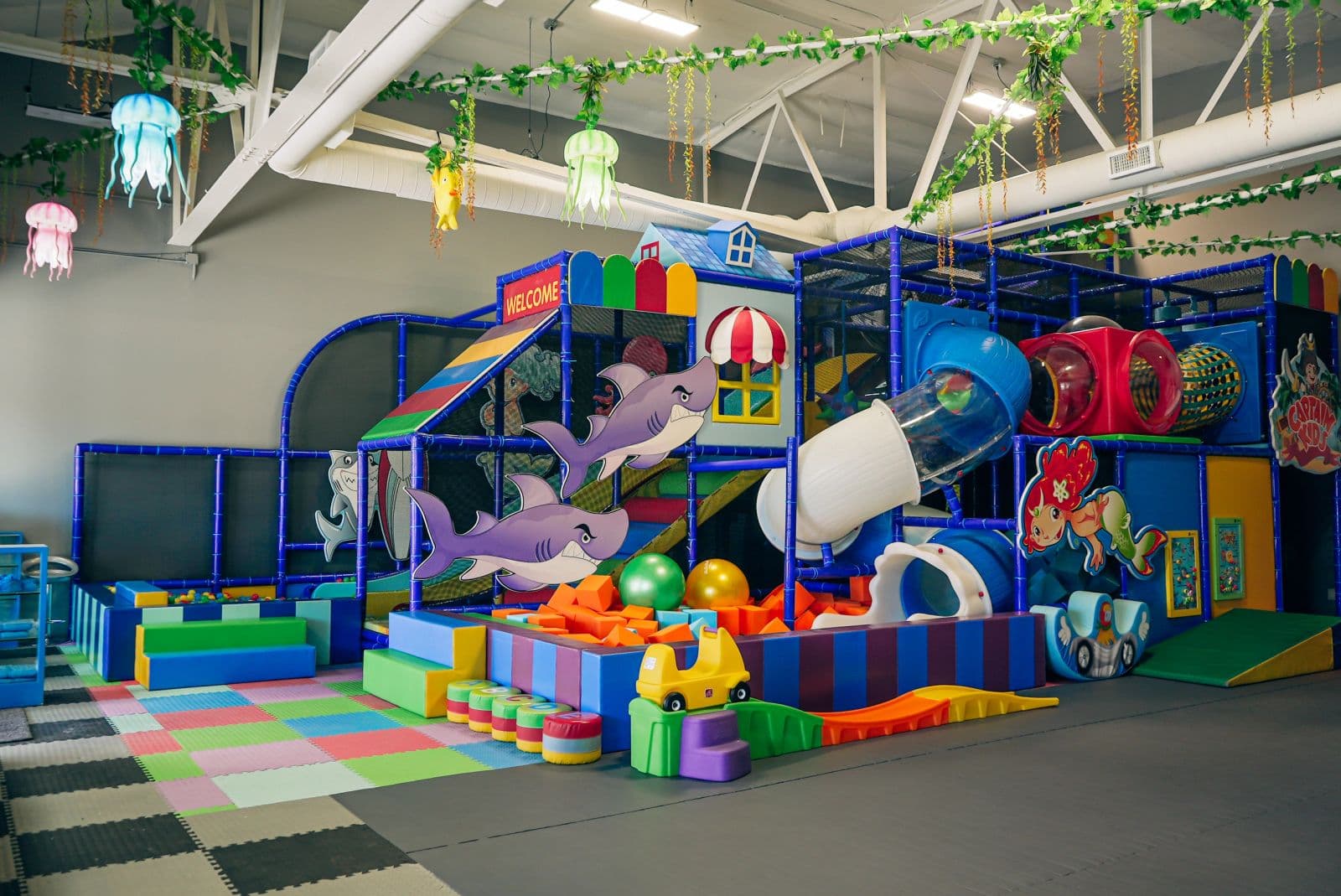 The play floor with the climbing structure, slides and ride-on toys
