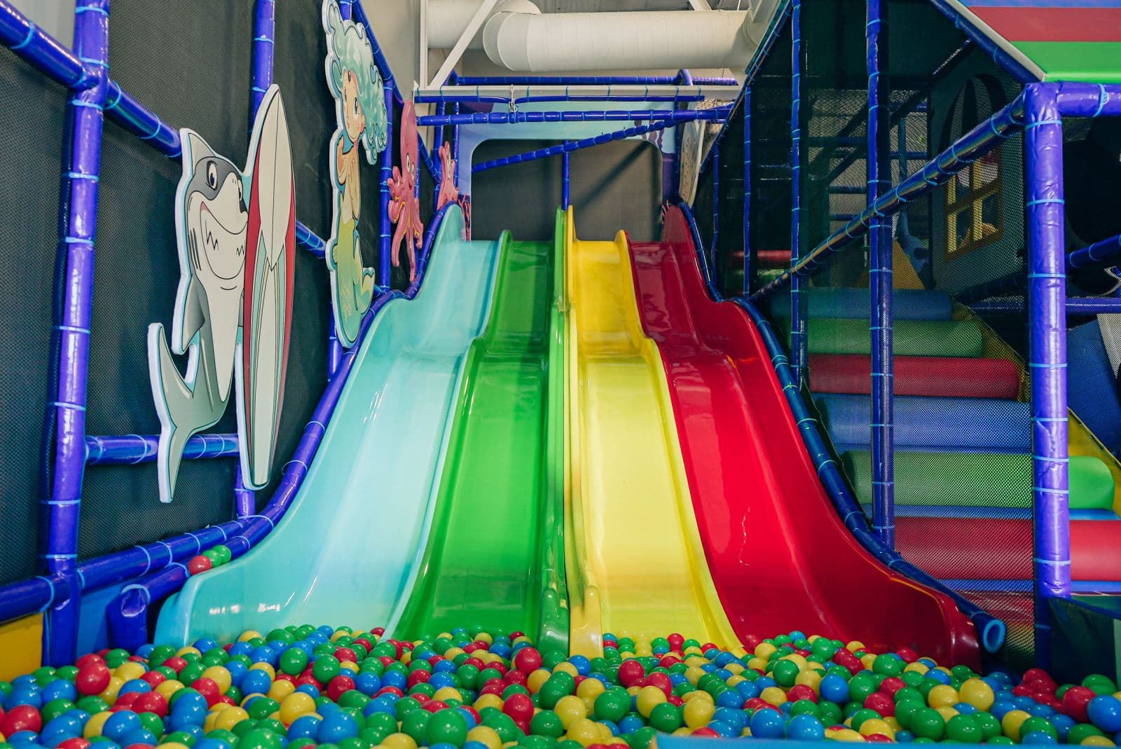 Three wide rainbow slides landing in a ball pit